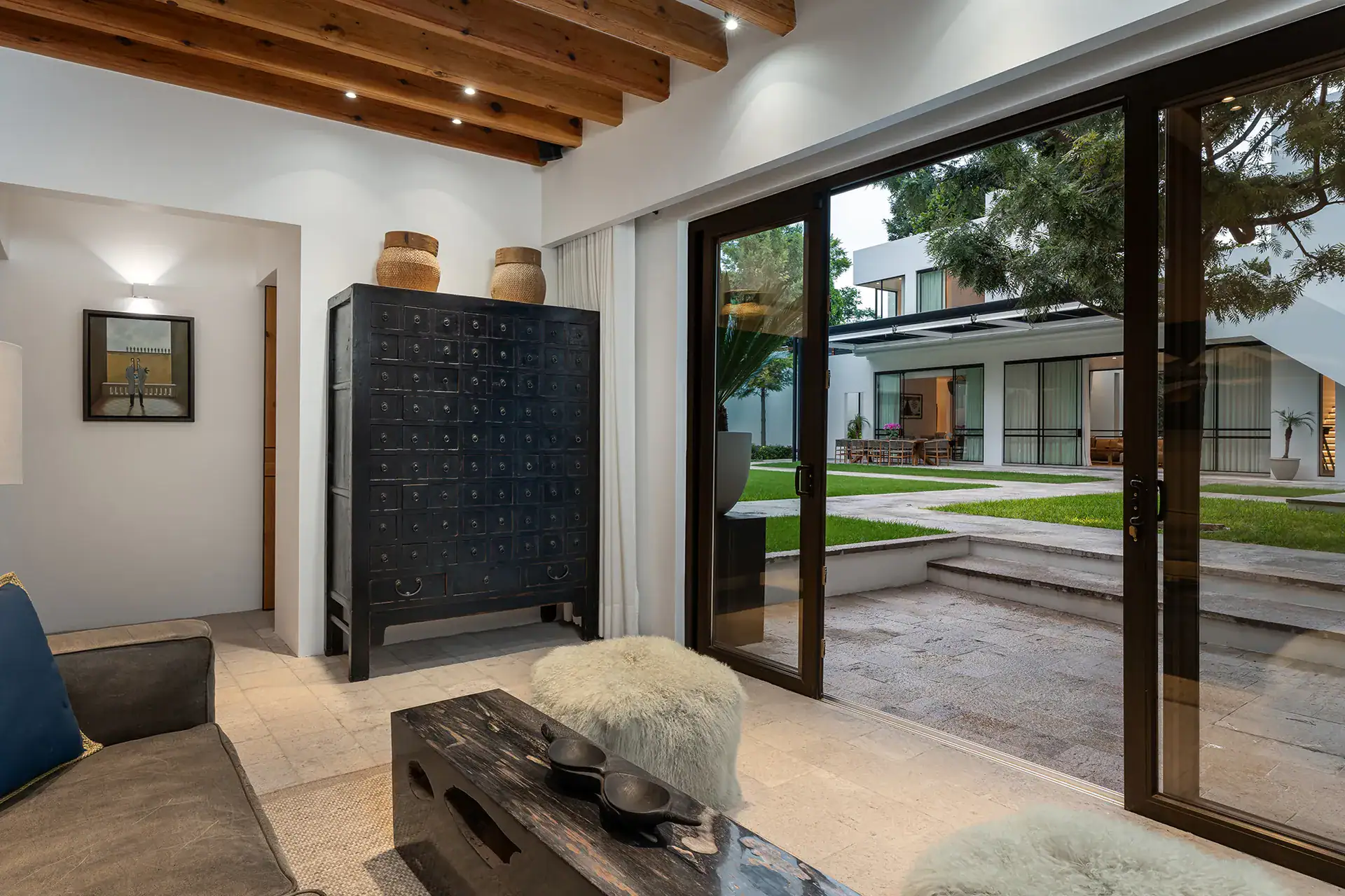 Villa del Parque Central, living room with an antique apothecary cabinet and sliding glass doors to the courtyard garden, San Miguel de Allende