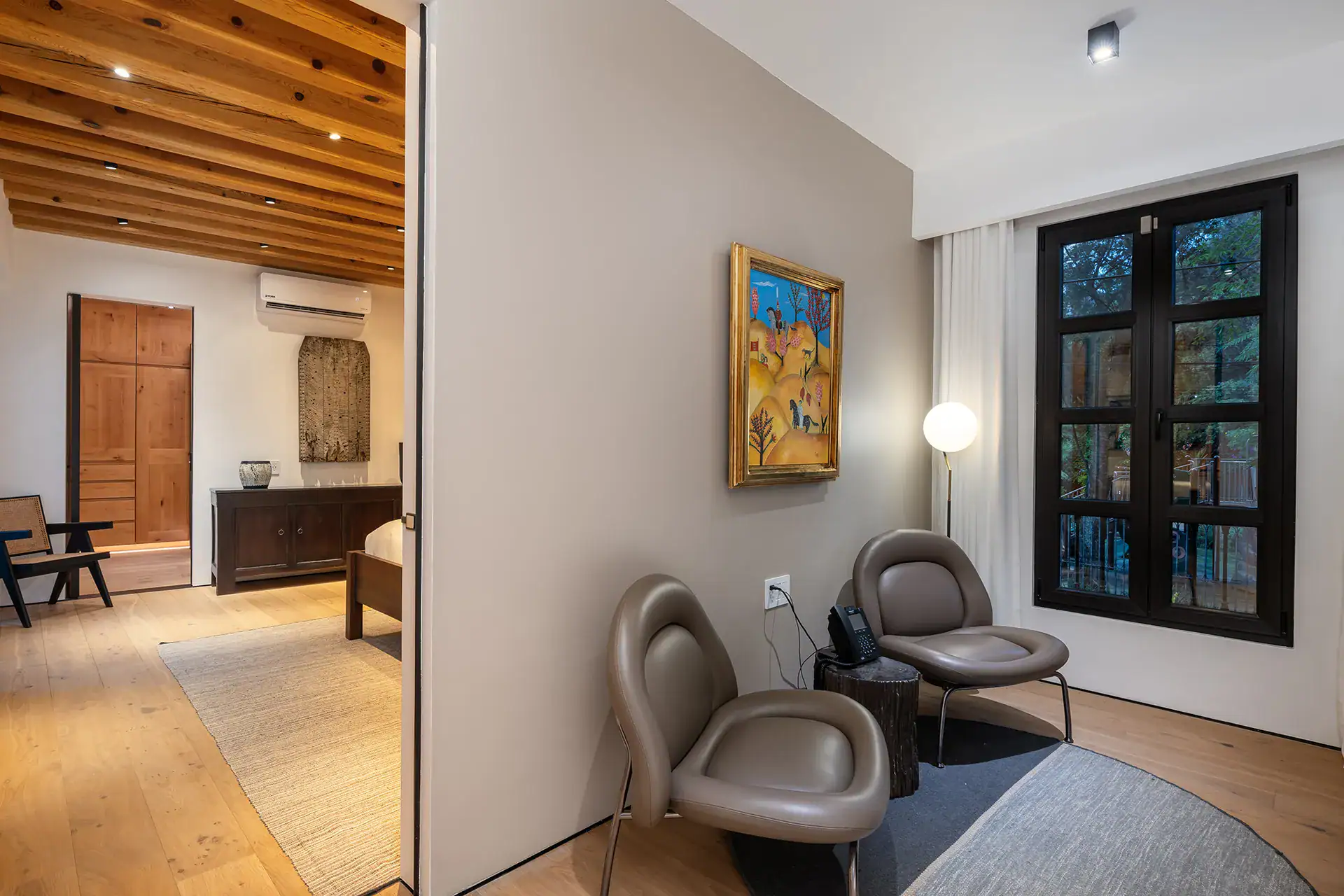 Villa del Parque Central, sitting nook with two modern chairs, a framed painting and black-framed windows, San Miguel de Allende