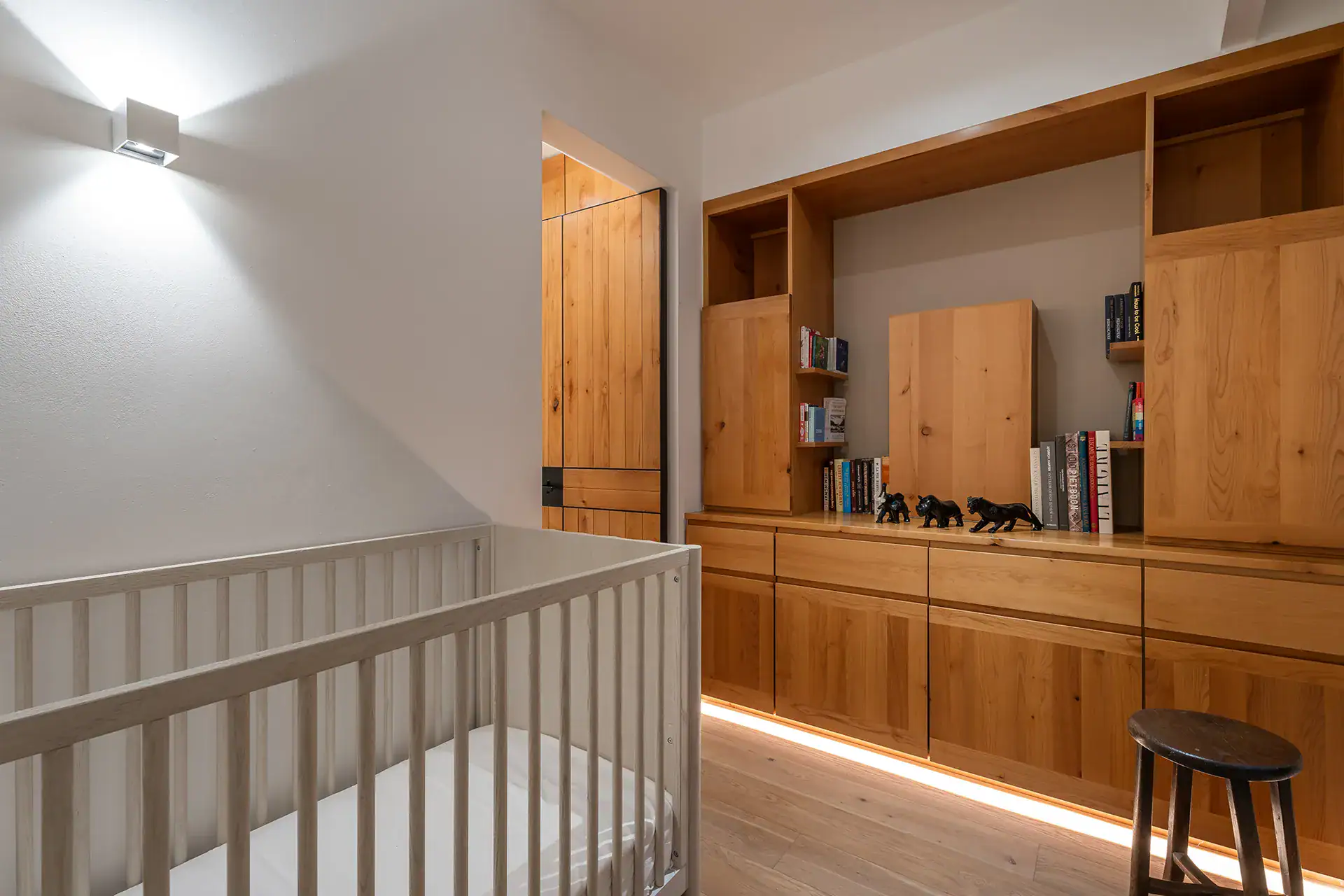 Villa del Parque Central, loft landing with a white railing, built-in oak bookshelves and a stool, San Miguel de Allende