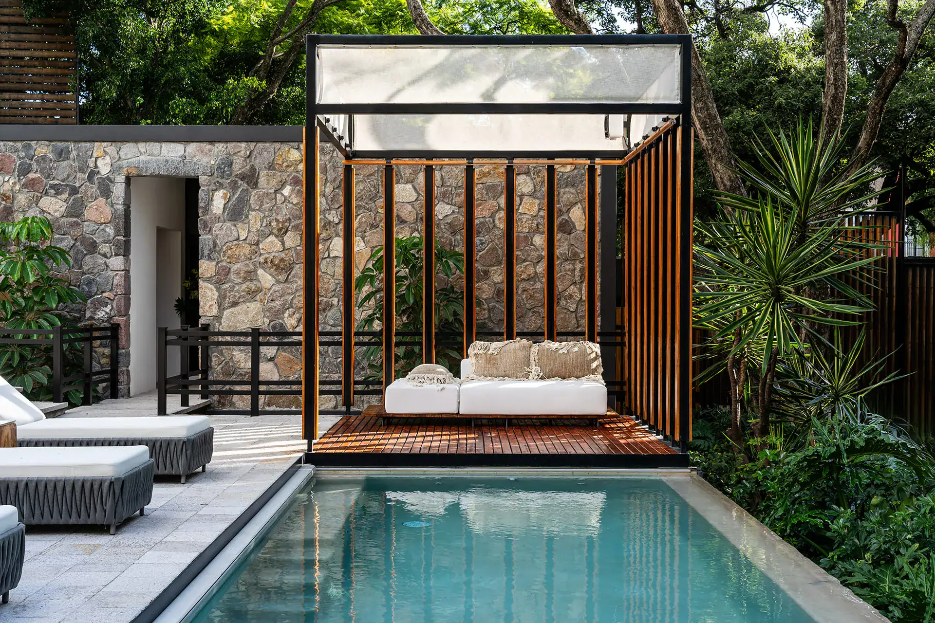 Villa del Parque Central, plunge pool with a wood-slat cabana daybed and lounge chairs beside a stone wall, San Miguel de Allende
