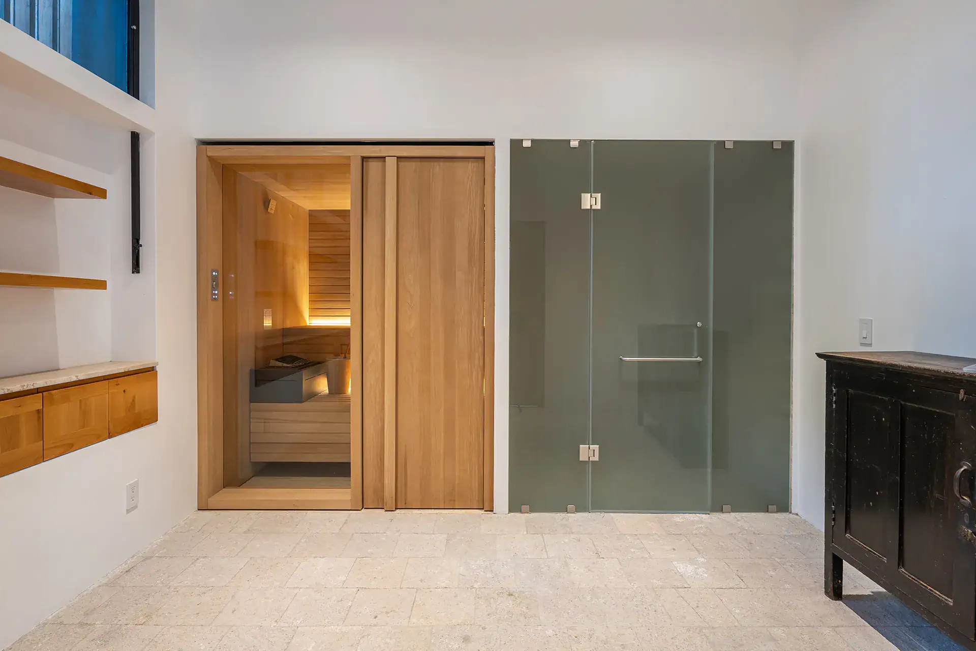 Villa del Parque Central, wood-paneled sauna door and frosted glass shower door in a stone-floored room, San Miguel de Allende