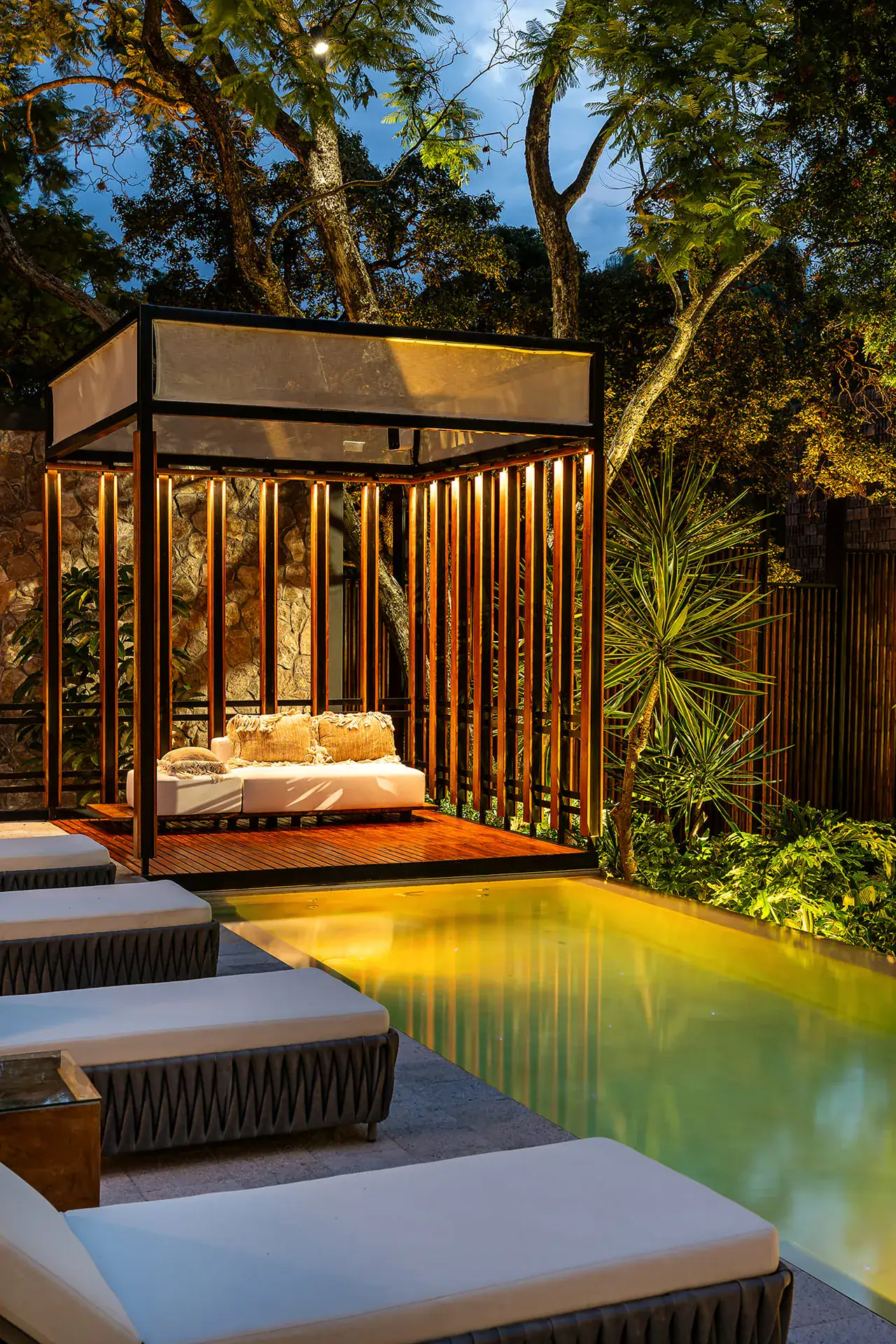 Villa del Parque Central, lit plunge pool and cabana at night with lounge chairs along the edge, San Miguel de Allende