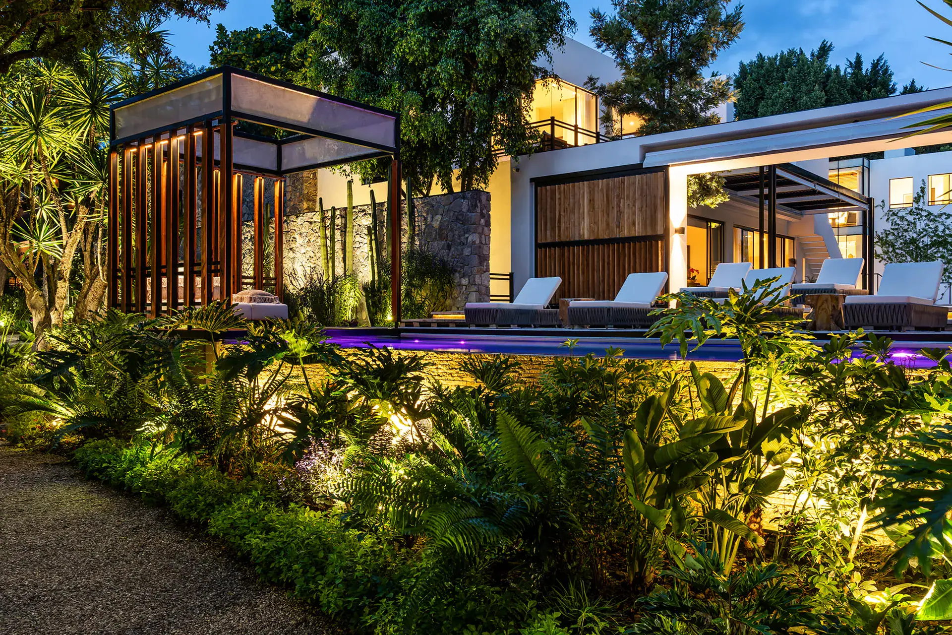 Villa del Parque Central, illuminated garden and pool cabana at dusk with the villa behind, San Miguel de Allende