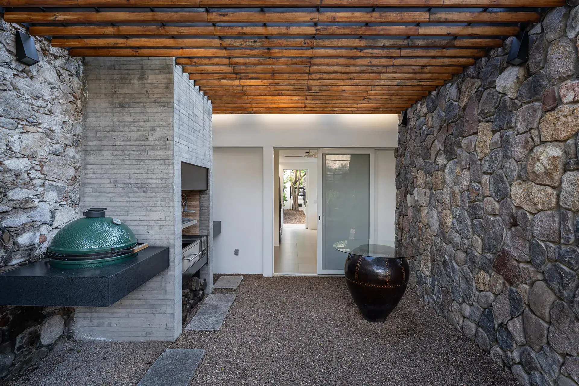 Villa del Parque Central, covered outdoor kitchen with a stone wall, grill and a bronze urn, San Miguel de Allende