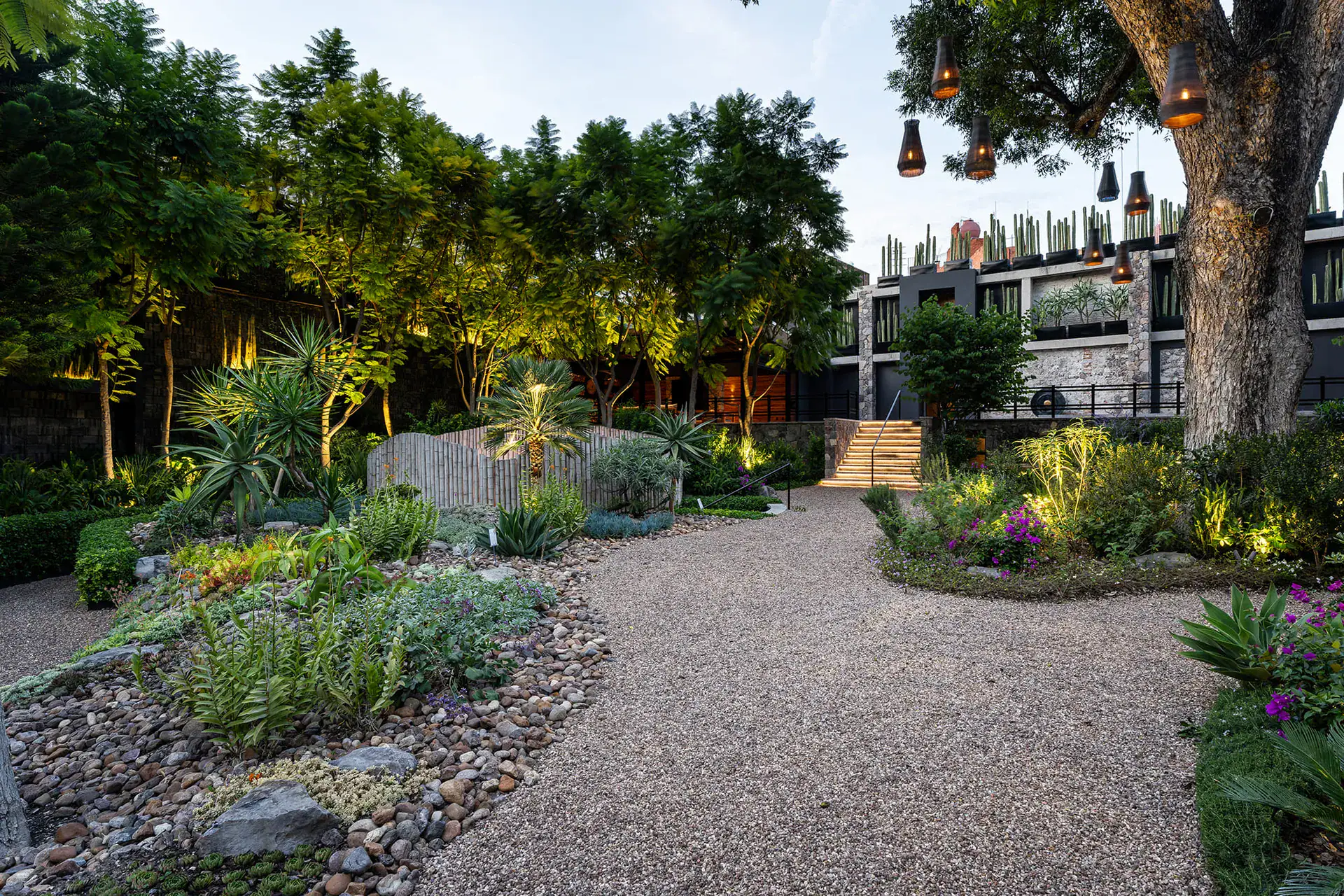Villa del Parque Central, gravel path winding through a landscaped garden toward a stepped stone wall, San Miguel de Allende