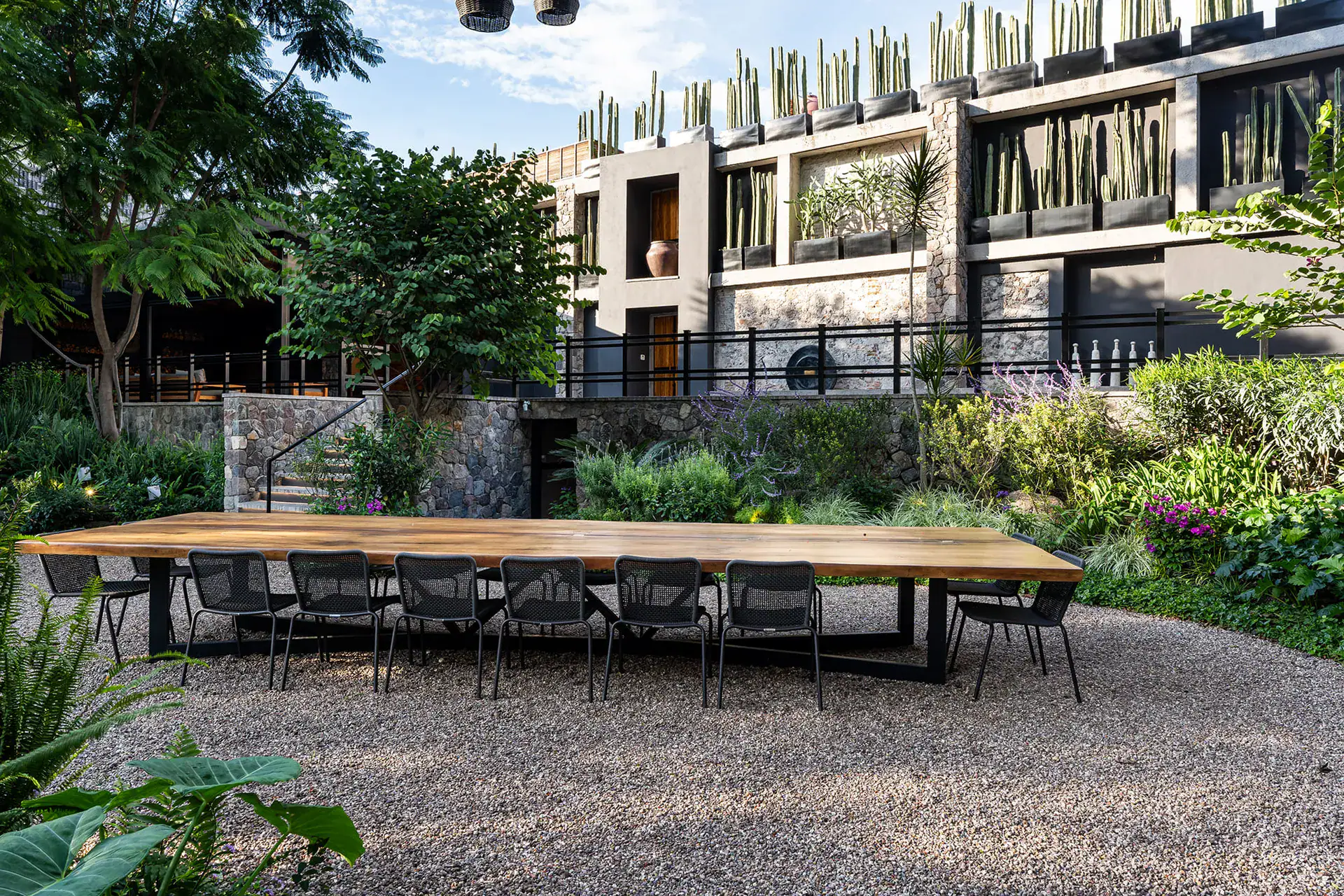 Villa del Parque Central, long outdoor dining table with black chairs on a gravel terrace in front of the villa, San Miguel de Allende