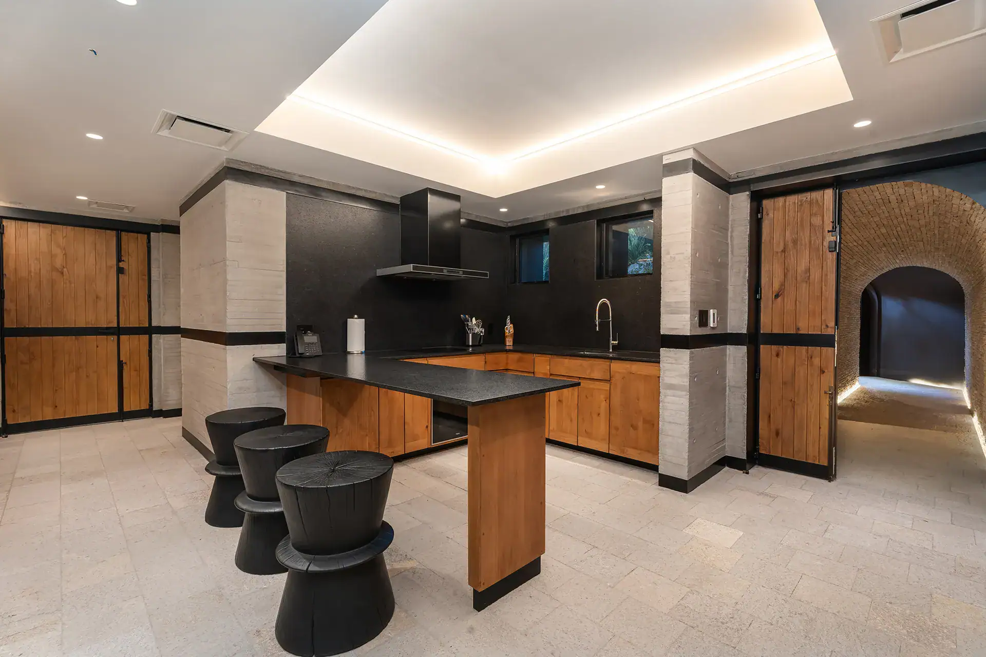 Villa del Parque Central, lower-level kitchen with a black bar island, black stools and oak doors, San Miguel de Allende