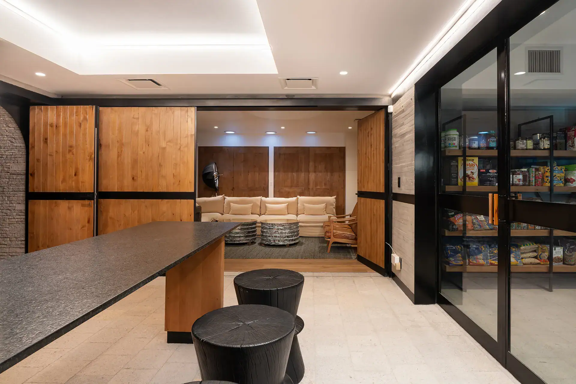 Villa del Parque Central, lower-level kitchen with a glass-door pantry and a sunken lounge beyond, San Miguel de Allende
