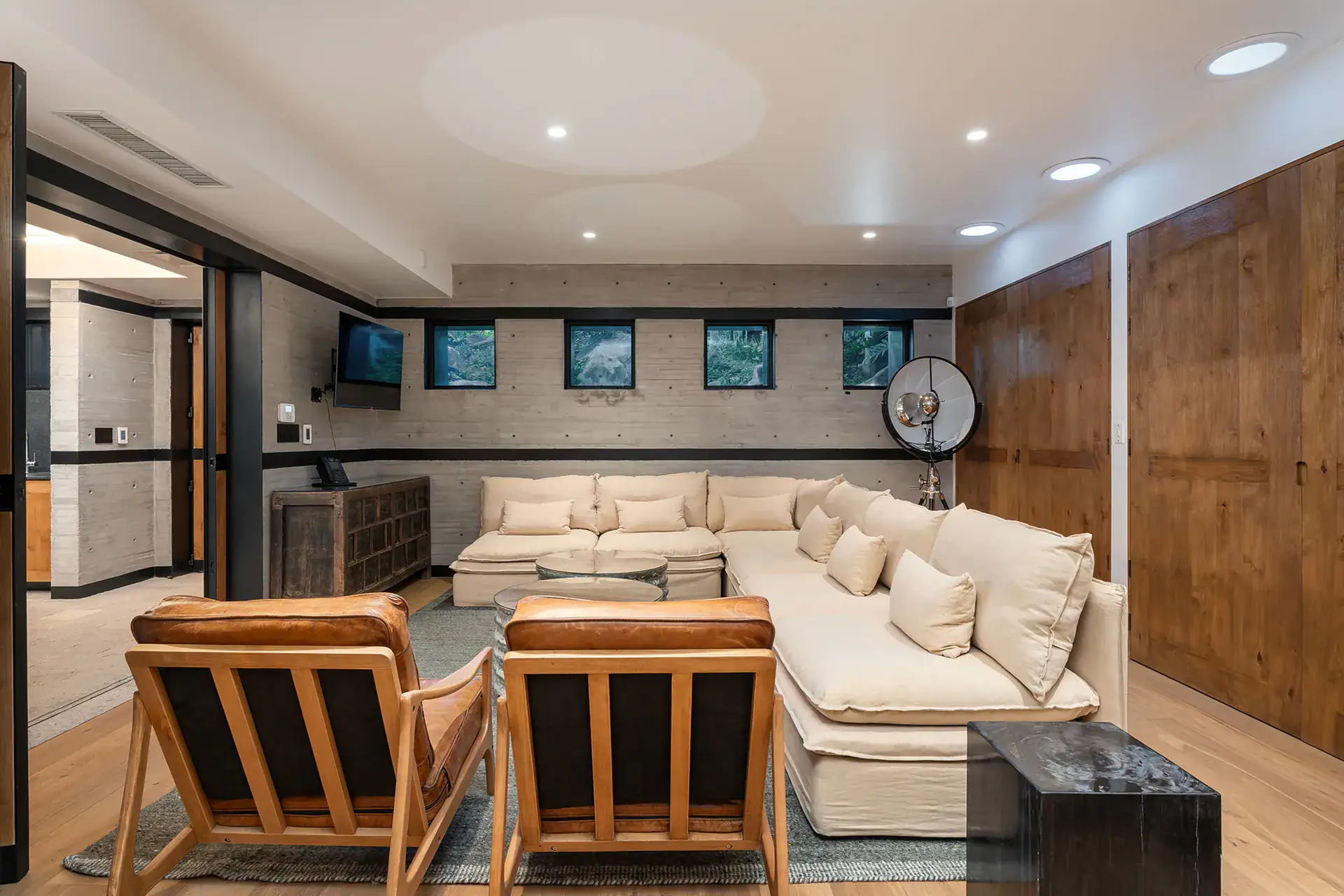 Villa del Parque Central, lower-level media lounge with a cream sectional, leather armchairs and oak doors, San Miguel de Allende