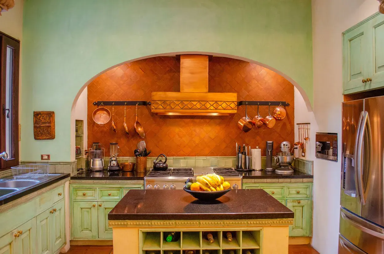 Villa Entre Sueños, kitchen with green cabinets, a copper hood and a butcher-block island, San Miguel de Allende