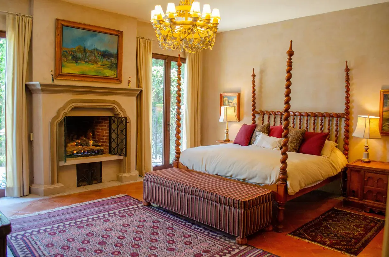 Villa Entre Sueños, primary bedroom with a four-poster bed, fireplace and chandelier, San Miguel de Allende