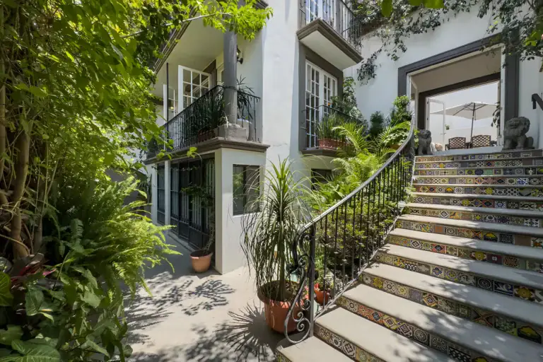 Villa Escondida, tiled staircase with an iron railing leading up through a leafy garden to a covered terrace, San Miguel de Allende