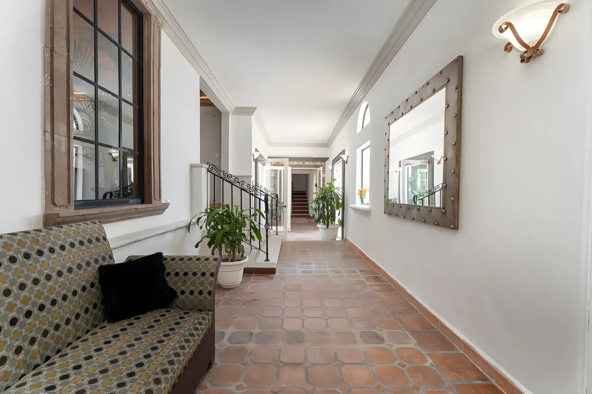 Villa Escondida, long corridor with a patterned bench and a framed mirror leading to a staircase, San Miguel de Allende
