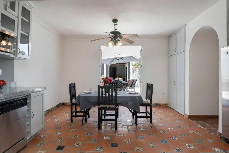 Villa Escondida, kitchen with a dining table, stainless dishwasher and white cabinets opening to a courtyard, San Miguel de Allende
