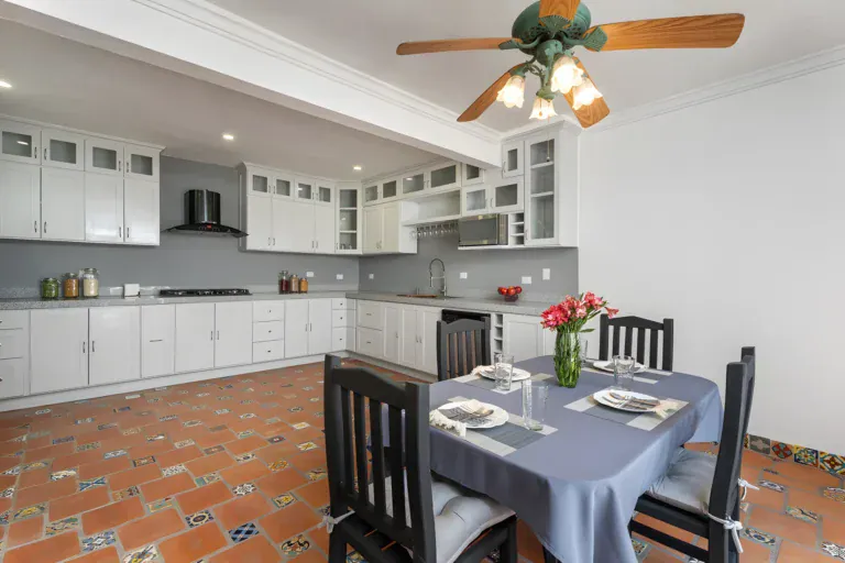 Villa Escondida, kitchen with white cabinets, black range hood and a gray-covered dining table, San Miguel de Allende