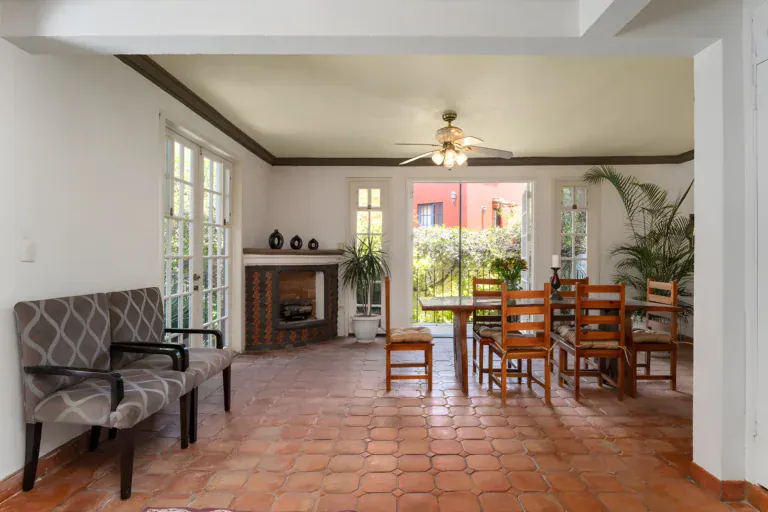 Villa Escondida, dining room with a wood table, a brick fireplace and French doors to the garden, San Miguel de Allende