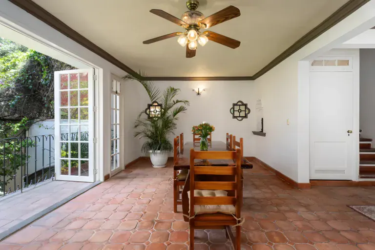 Villa Escondida, dining room with a carved wood table, an open French door and a staircase, San Miguel de Allende