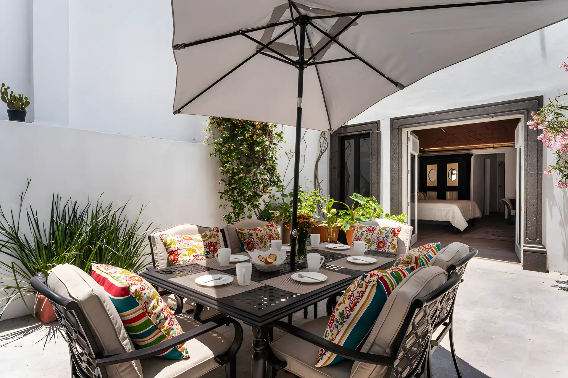 Villa Escondida, patio dining table with an umbrella and colorful cushions outside a bedroom, San Miguel de Allende