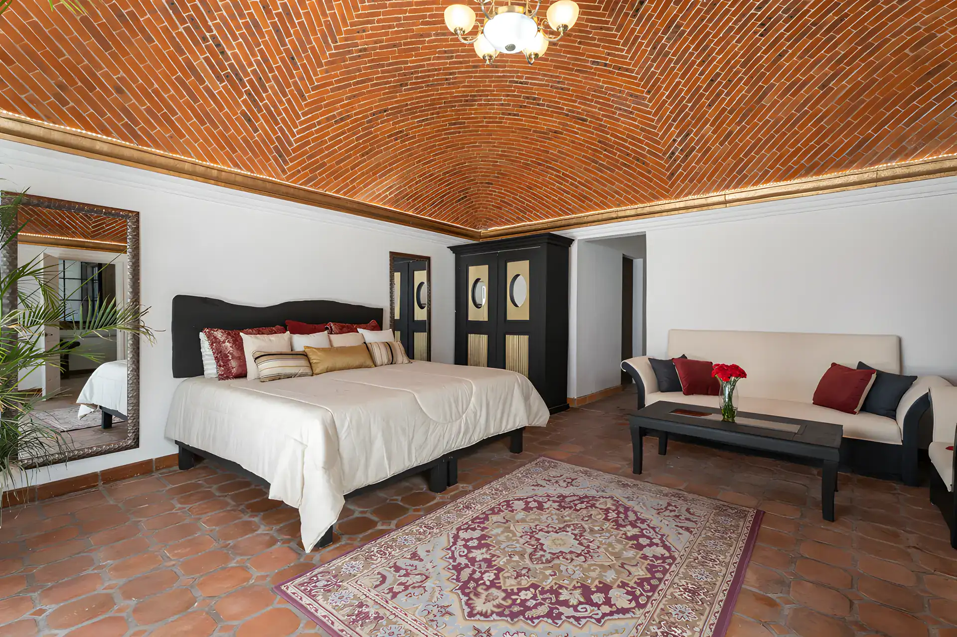Villa Escondida, bedroom with a king bed, brick vaulted ceiling, black armoire and a sofa, San Miguel de Allende