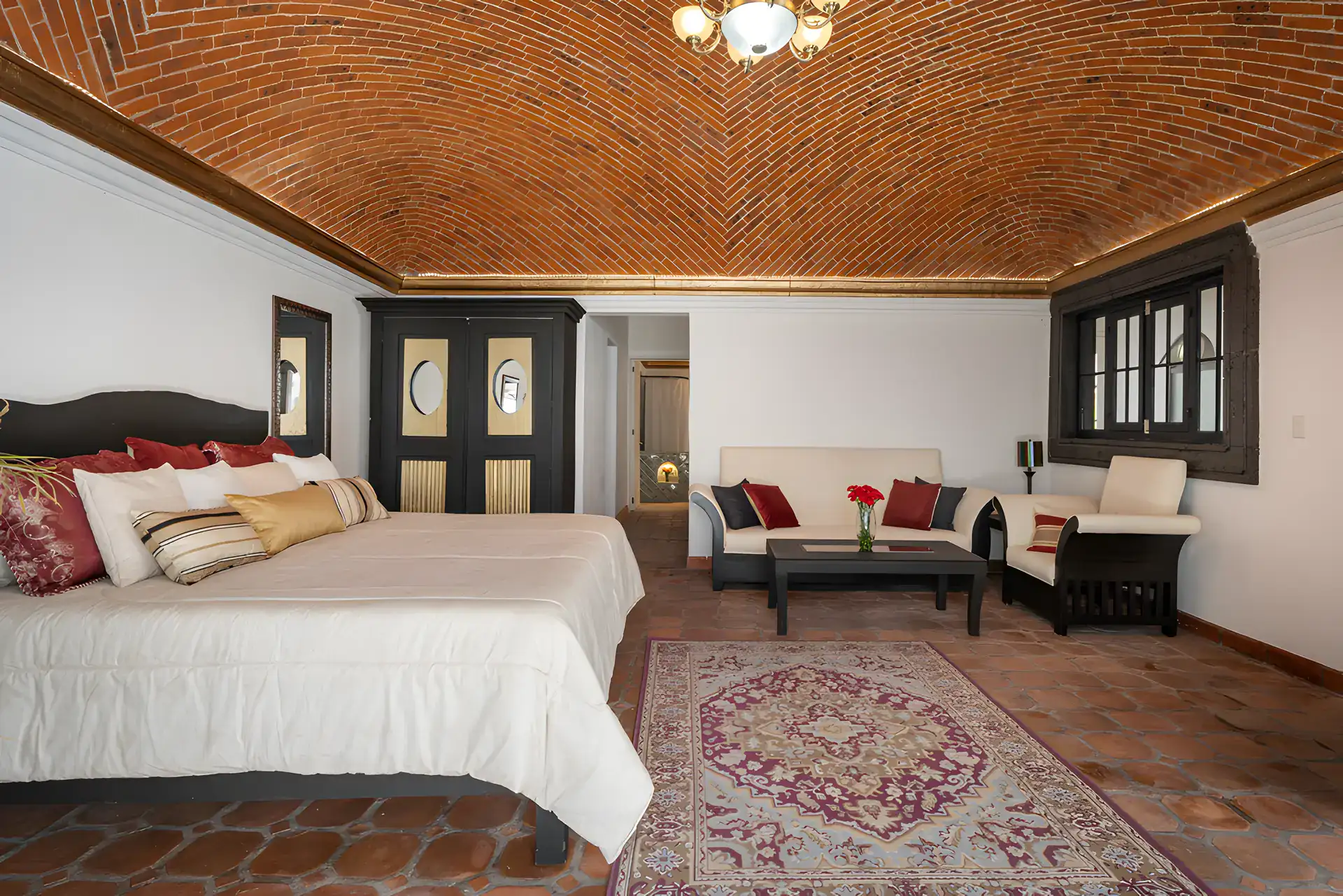 Villa Escondida, bedroom with a king bed, area rug and a seating area under a brick vaulted ceiling, San Miguel de Allende