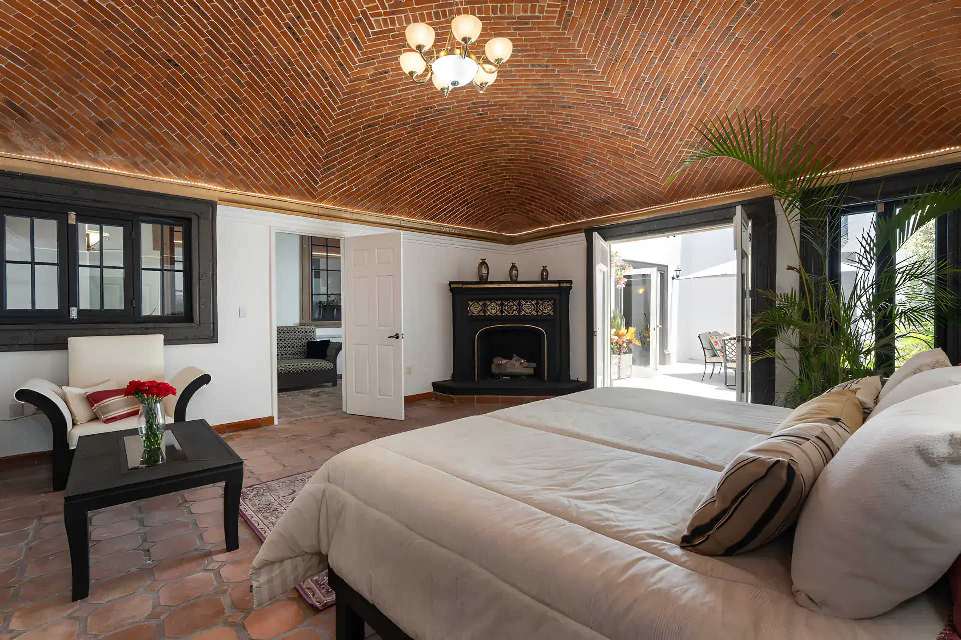 Villa Escondida, bedroom with a corner fireplace, an armchair and a brick vaulted ceiling, San Miguel de Allende