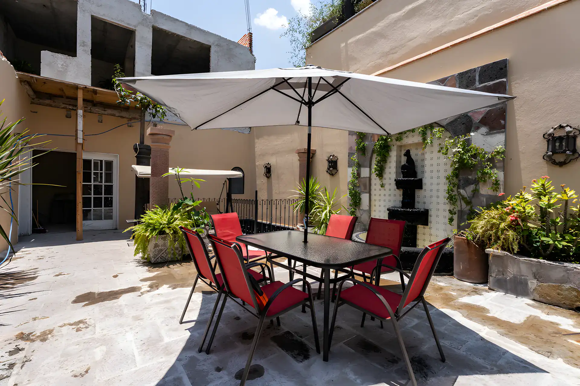 Villa Escondida, terrace with a dining set and a fountain with a pergola swing beyond, San Miguel de Allende