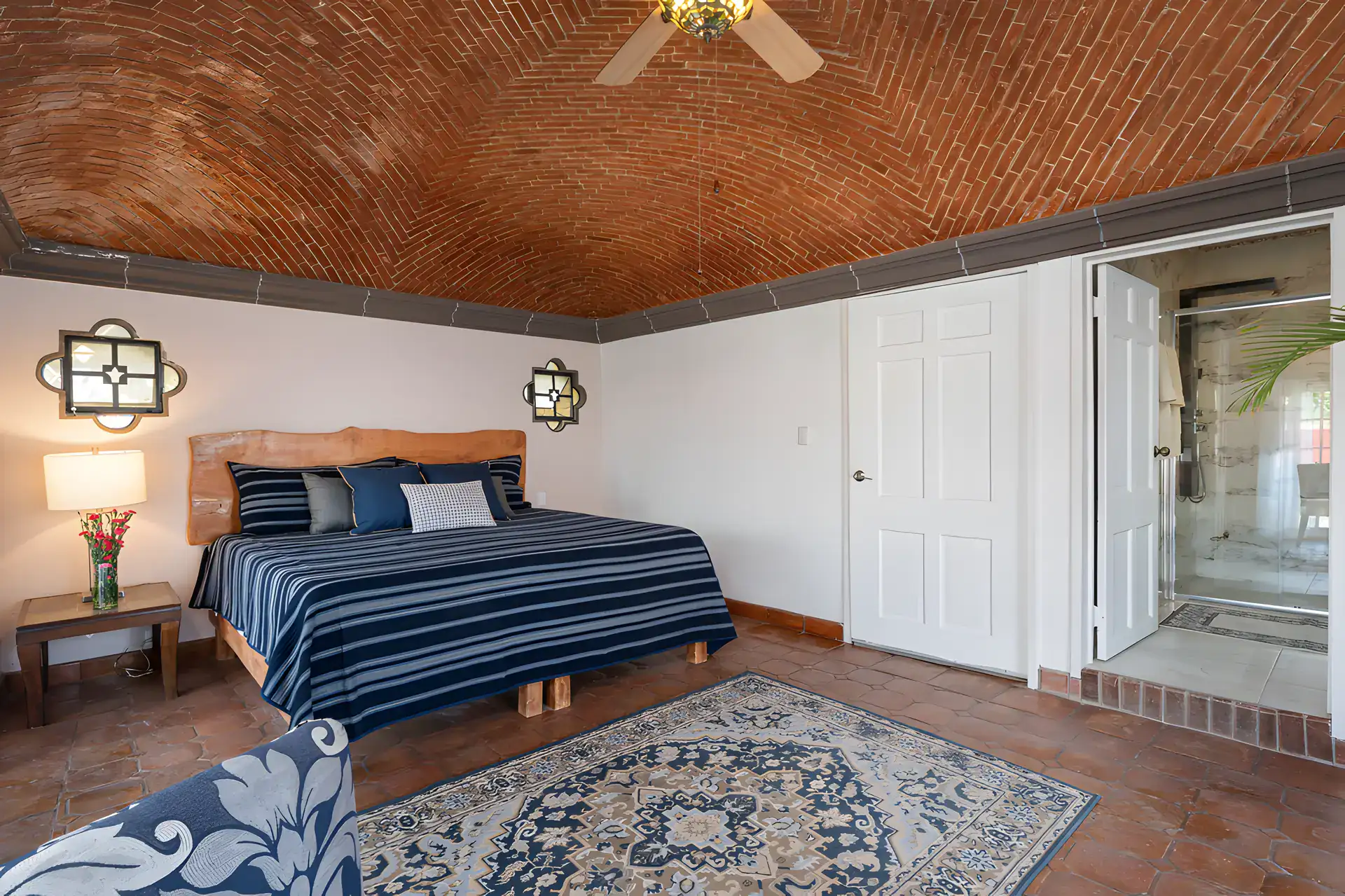 Villa Escondida, bedroom with a navy striped bed, rug and an en suite bathroom beyond, San Miguel de Allende