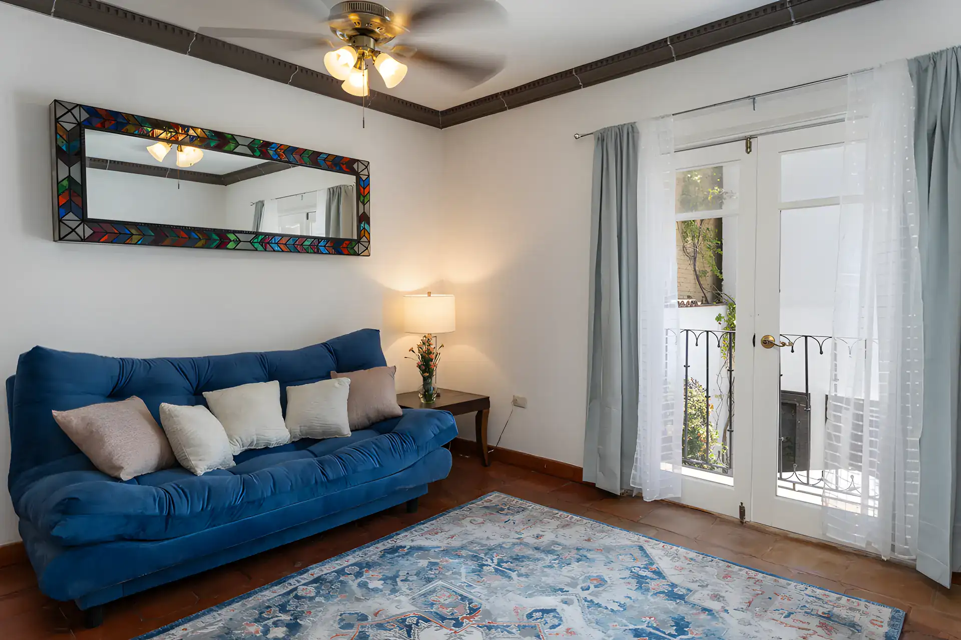 Villa Escondida, bedroom with a blue sofa, a tiled-frame mirror and French doors to a balcony, San Miguel de Allende