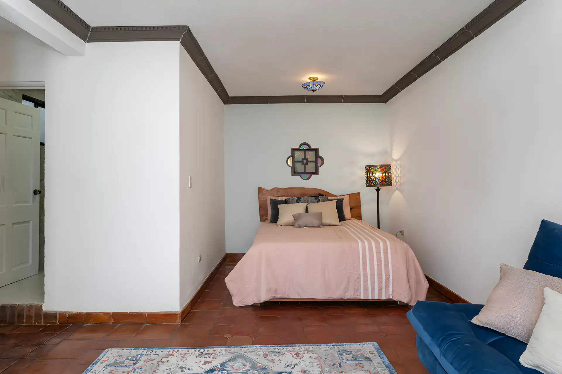 Villa Escondida, bedroom with a pink bedspread, wood headboard and a blue sofa, San Miguel de Allende