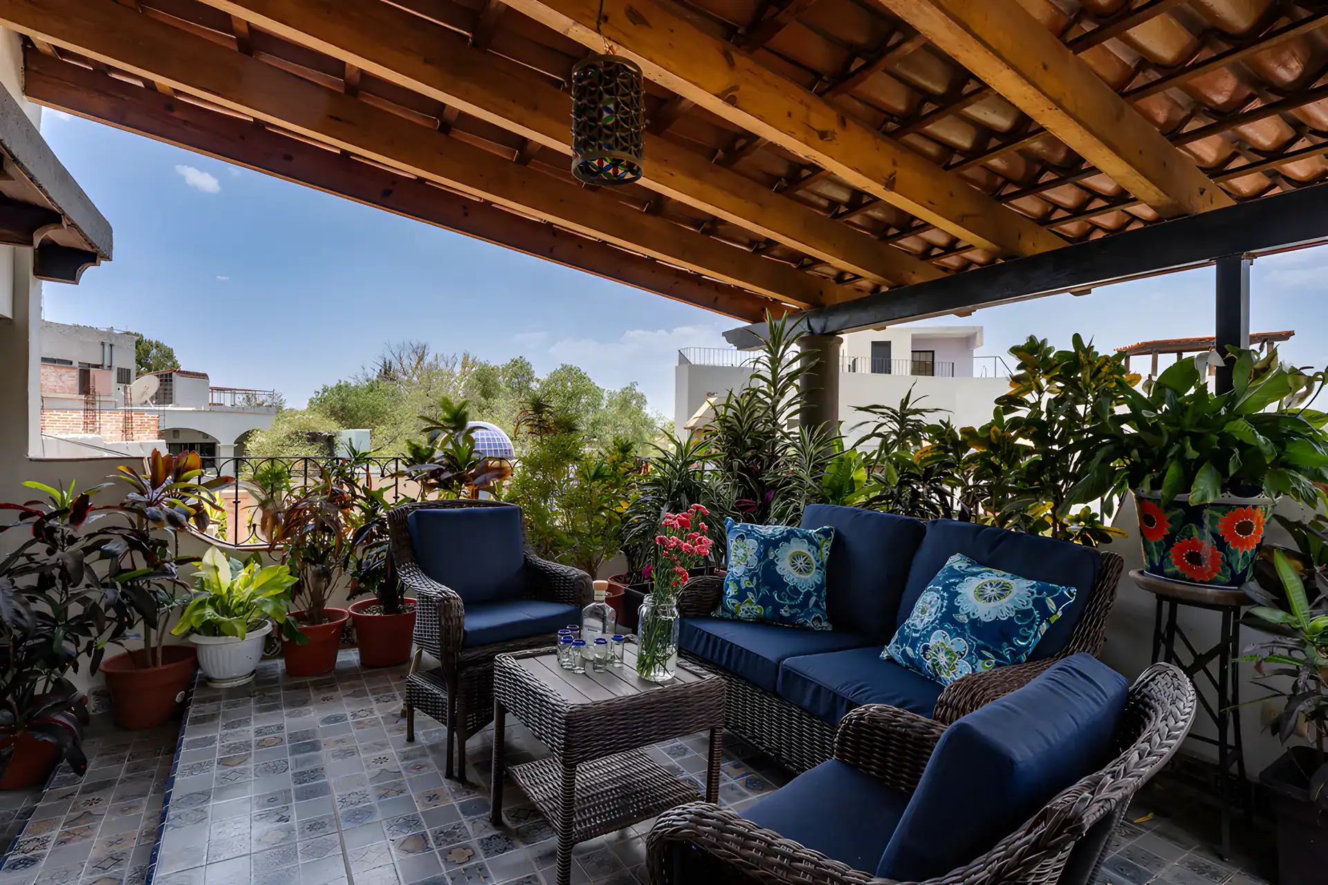 Villa Escondida, terrace seating under a wood-beam roof with potted plants and a view to the hills, San Miguel de Allende