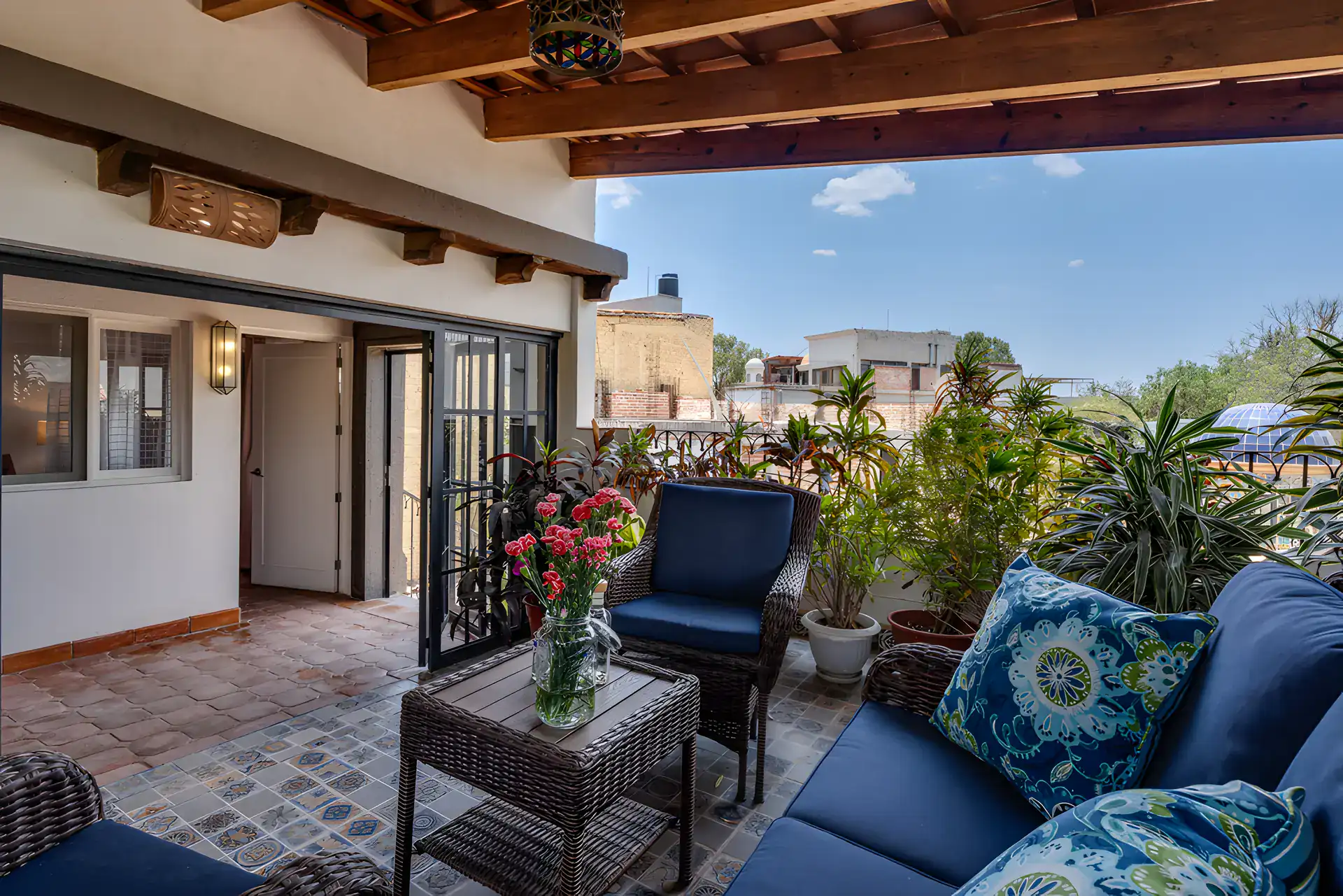 Villa Escondida, terrace with blue wicker sofas, a glass table and a beamed ceiling above the bedroom, San Miguel de Allende