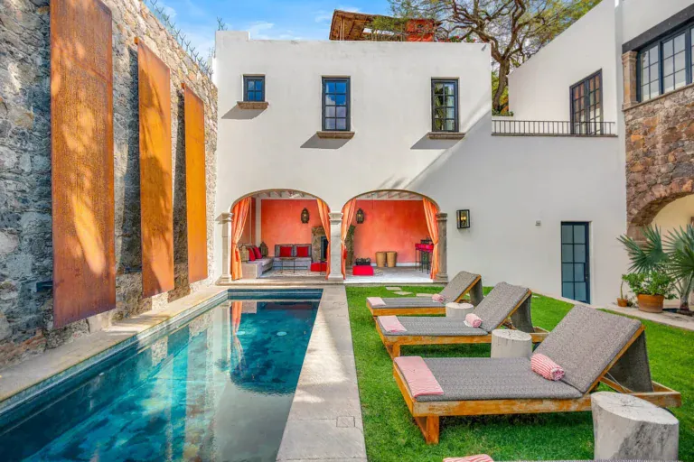Villa Garita, lap pool with lounge chairs and a stone wall with weathered steel panels, San Miguel de Allende