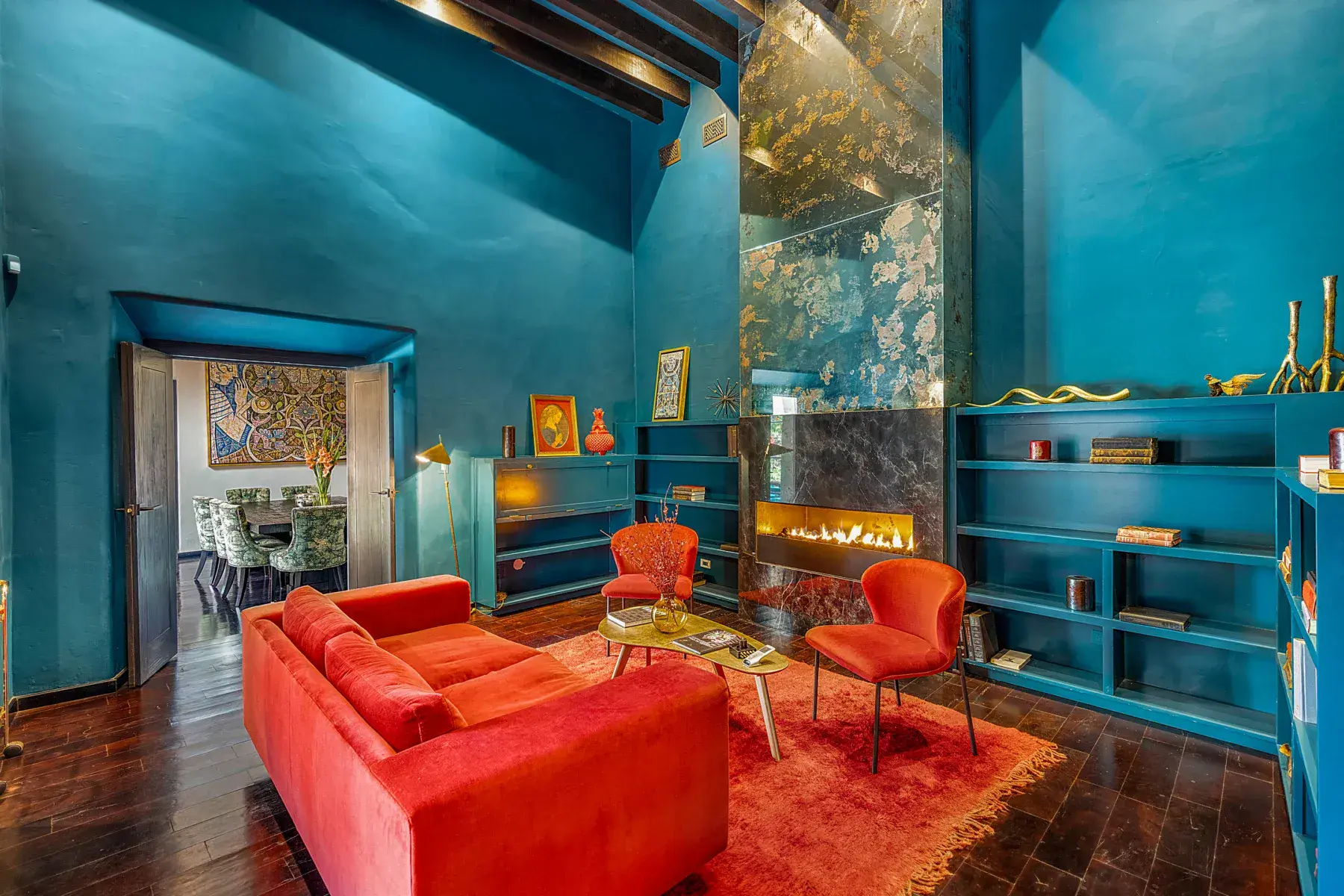 Villa Garita, living room with teal walls, a red sofa and a linear fireplace, San Miguel de Allende