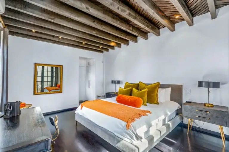 Villa Garita, bedroom with orange bedding, gold pillows and a beamed ceiling, San Miguel de Allende