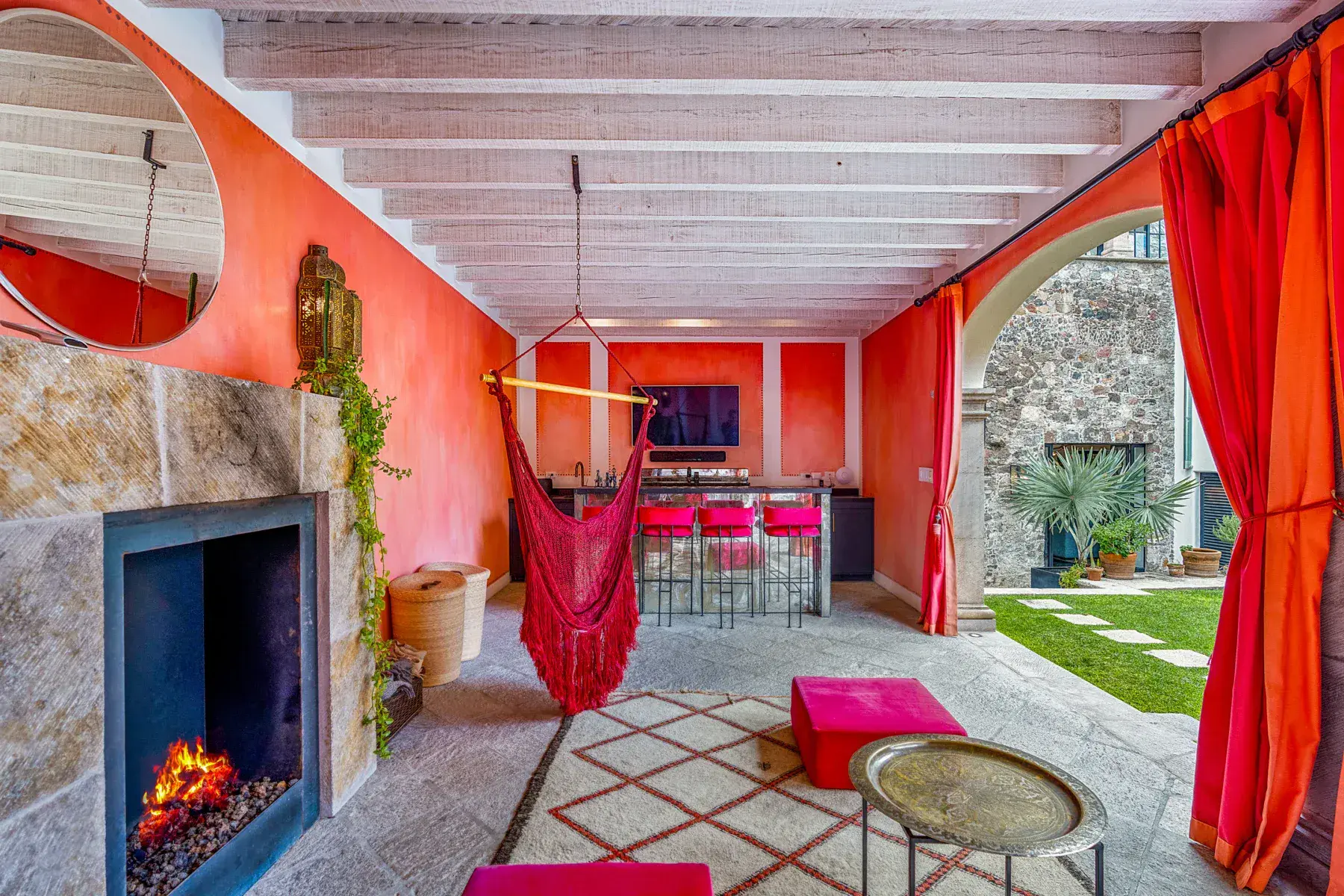 Villa Garita, covered lounge with a fireplace, hammock chair and red curtains, San Miguel de Allende