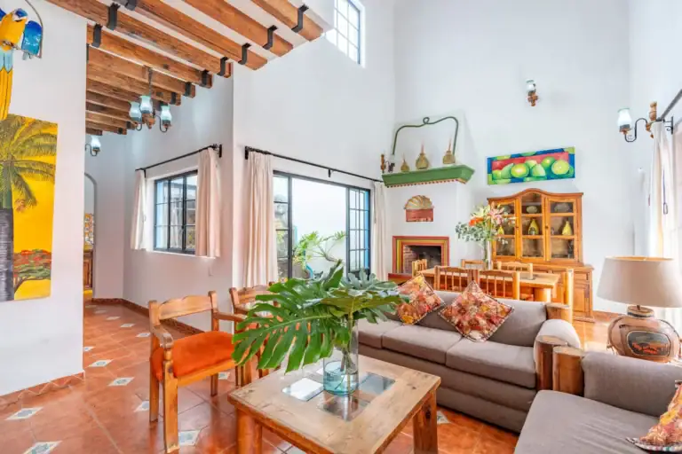 Villa Guacamayas, living and dining area with a gray sofa, beamed ceiling and a rustic wood hutch, San Miguel de Allende