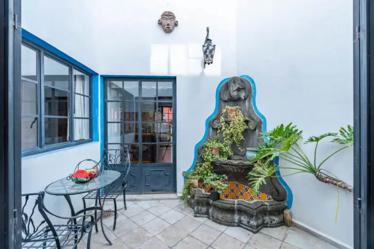 Villa Guacamayas, small patio with a bistro table and a tiled wall fountain beside a glass door, San Miguel de Allende
