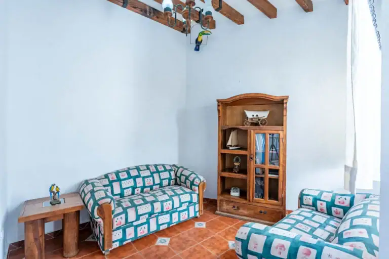 Villa Guacamayas, sitting room with a patterned sofa, wood hutch and a beamed ceiling, San Miguel de Allende