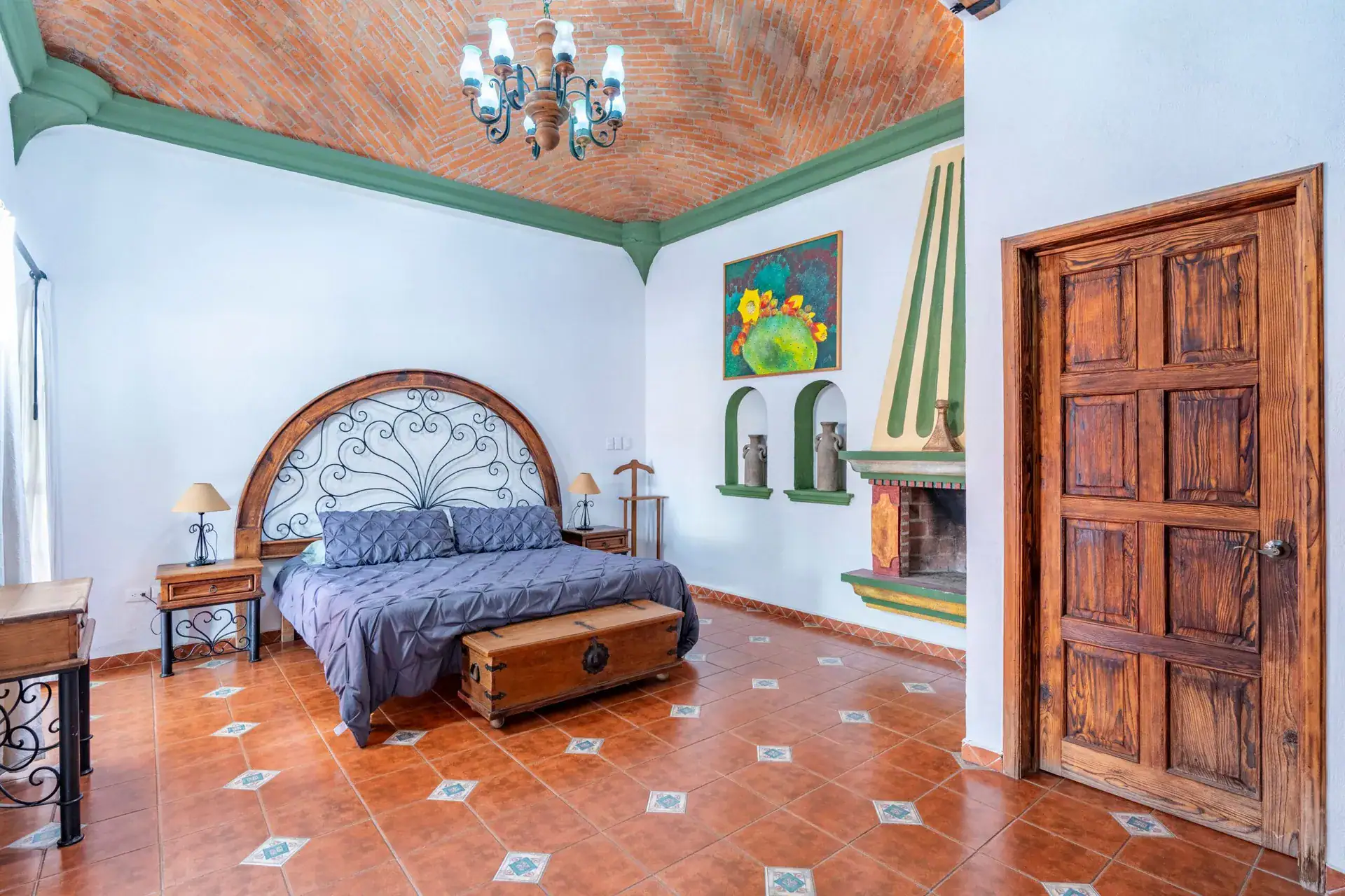 Villa Guacamayas, bedroom with a king bed, wrought-iron headboard, corner fireplace and brick vaulted ceiling, San Miguel de Allende