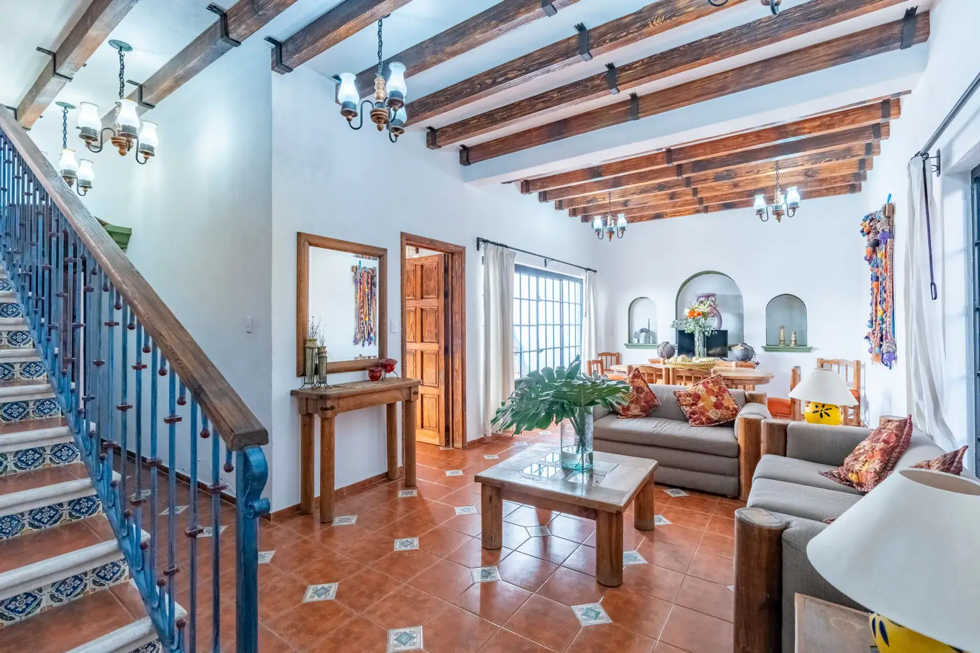 Villa Guacamayas, entry hall with a tiled staircase and a view into the living and dining area, San Miguel de Allende