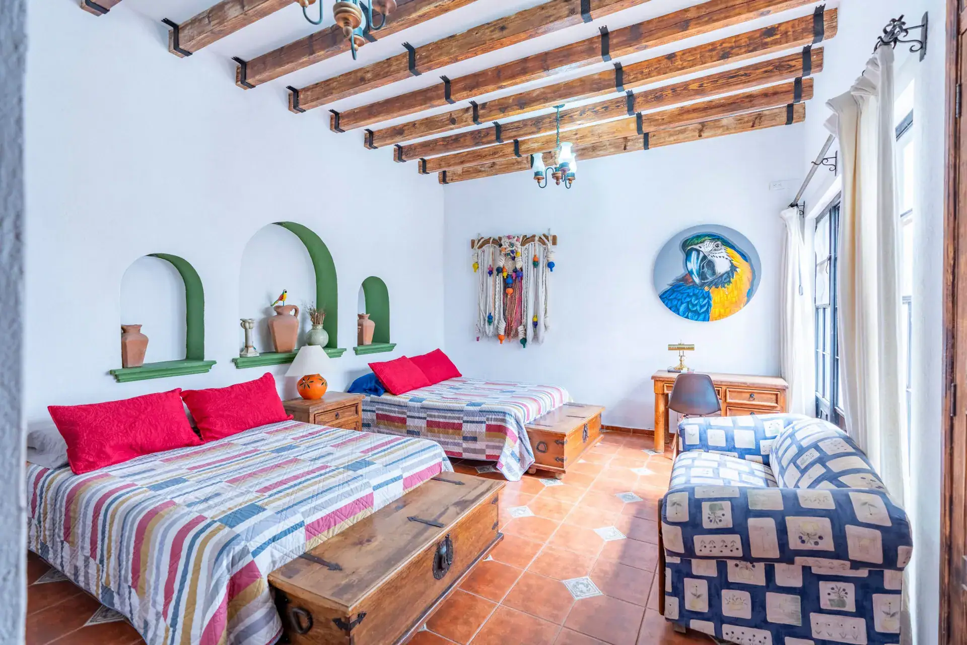 Villa Guacamayas, bedroom with two beds in striped bedding, a desk and a patterned sofa under a beamed ceiling, San Miguel de Allende