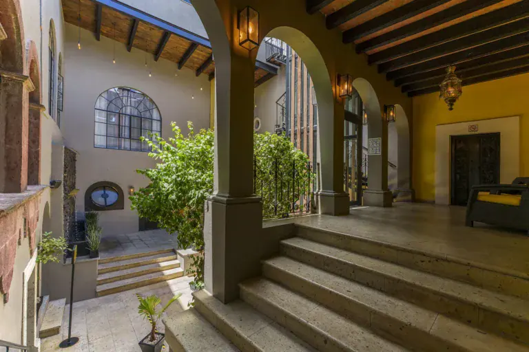 Villa Limón, arcaded courtyard with stone steps and plants, San Miguel de Allende