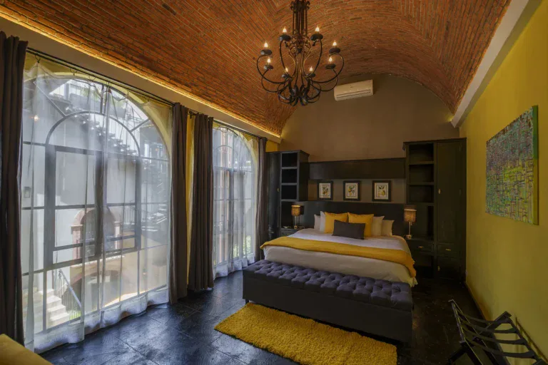 Villa Limón, bedroom with a vaulted brick ceiling, arched windows and a yellow accent wall, San Miguel de Allende