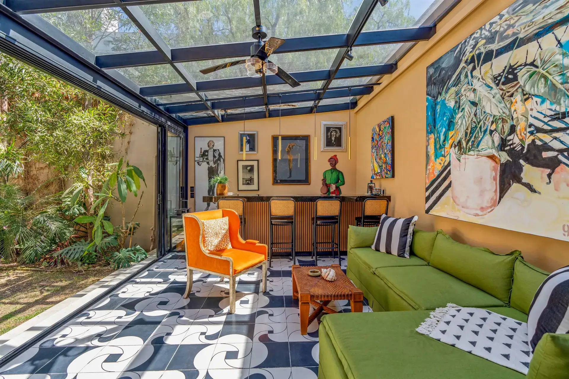 Villa Pacifica, glass-roofed lounge with a green sectional, an orange armchair, a bar and a black and white patterned floor, San Miguel de Allende