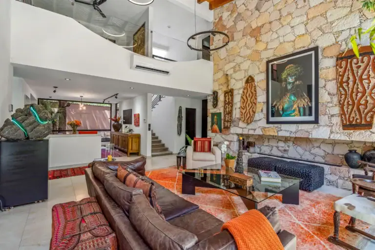 Villa Pacifica, living area with a stone wall, a leather sectional, a glass coffee table and a loft above, San Miguel de Allende