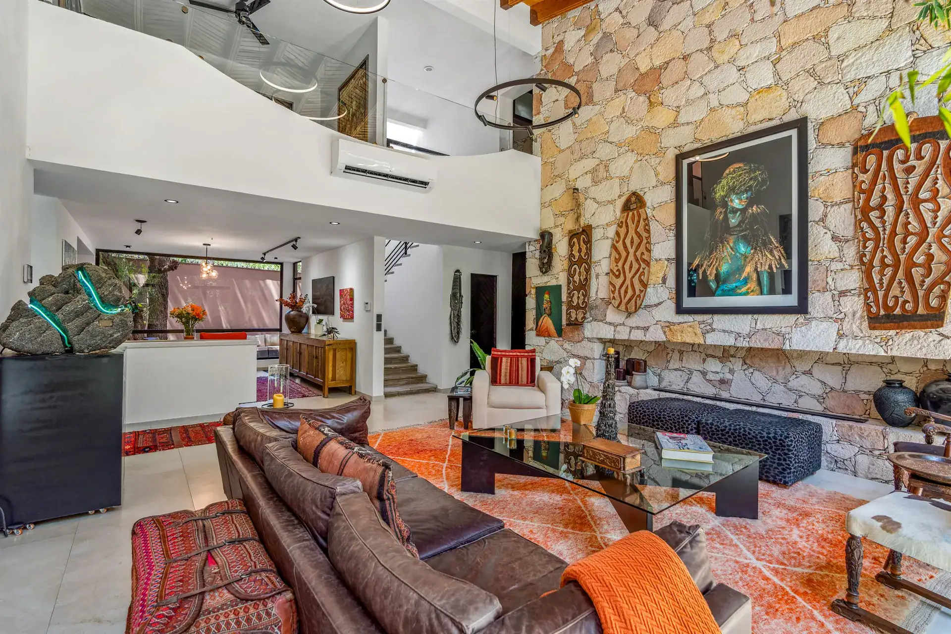 Villa Pacifica, living area with a stone wall, a leather sectional, a glass coffee table and a loft above, San Miguel de Allende