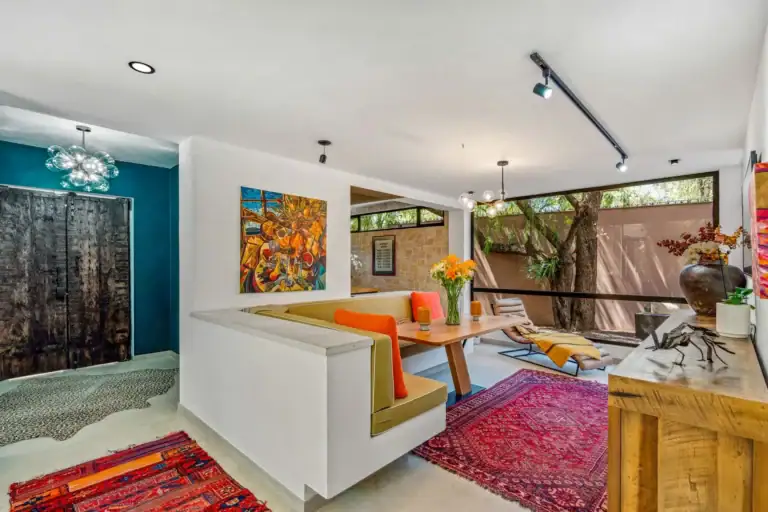 Villa Pacifica, sunken seating area with a teal wall, a carved door and an orange-cushioned banquette, San Miguel de Allende