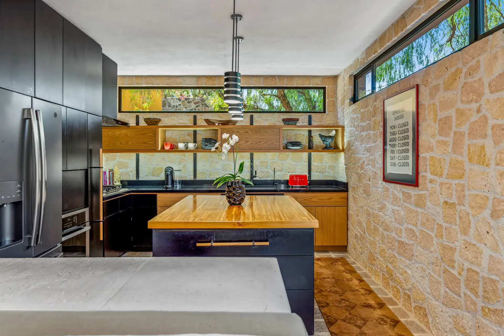 Villa Pacifica, kitchen with a stone wall, open shelves and a clerestory window above the island, San Miguel de Allende