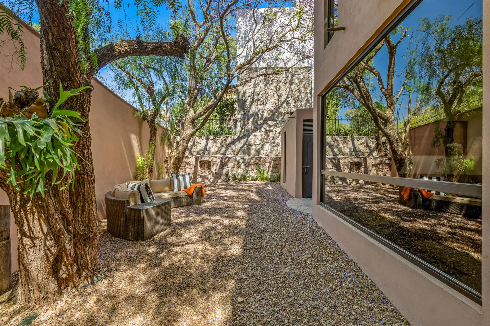 Villa Pacifica, side garden with a gravel yard, tall trees and a lounge chair set, San Miguel de Allende