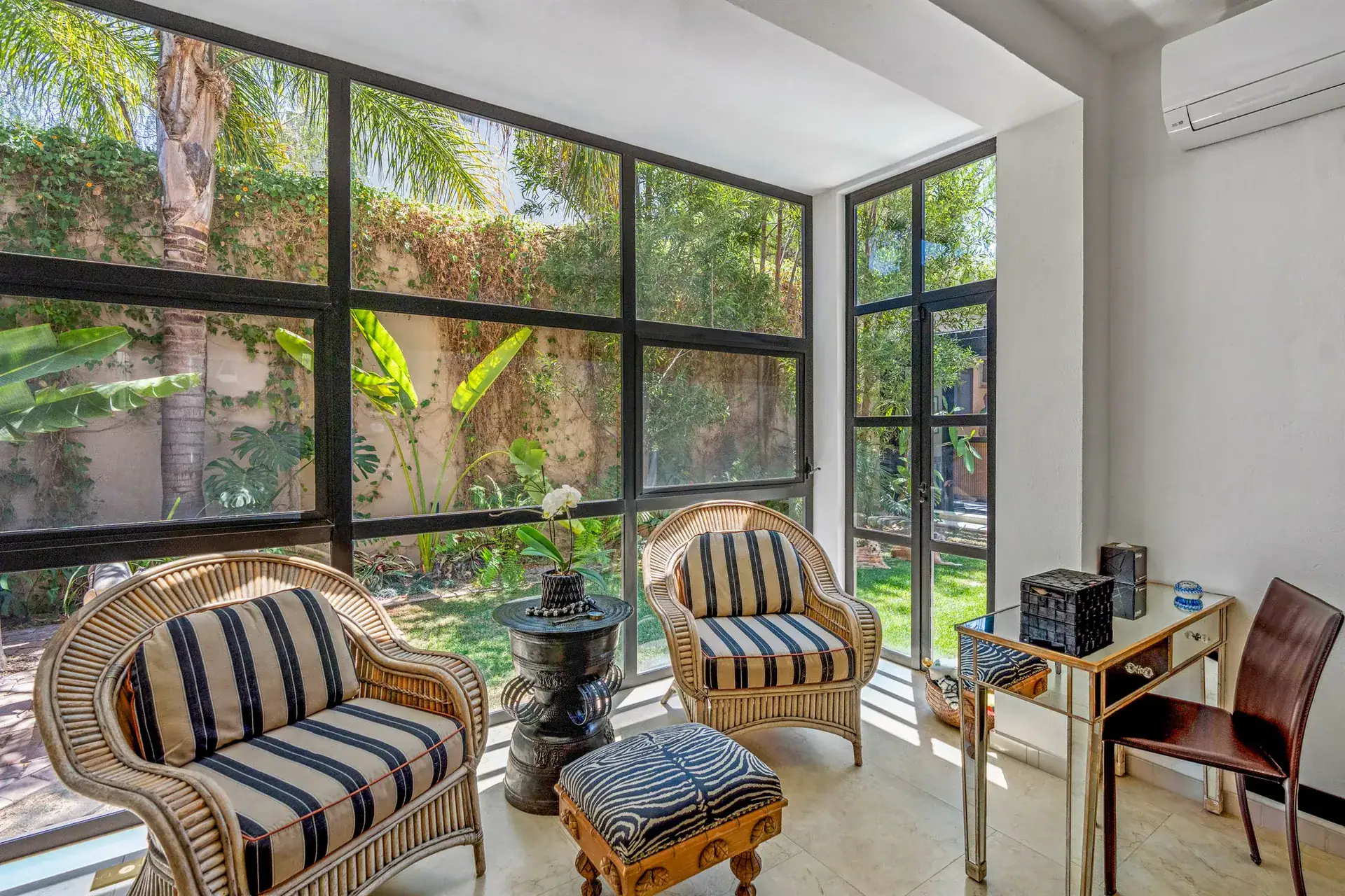 Villa Pacifica, sunroom sitting area with striped wicker chairs, a desk and floor-to-ceiling garden windows, San Miguel de Allende